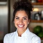 Portrait of Chef Maria Santos, a vibrant plant-based nutrition expert smiling warmly.